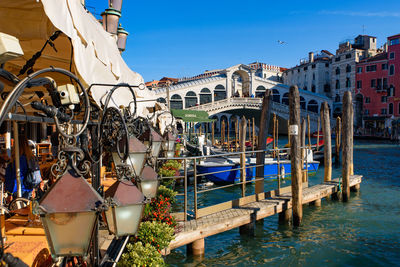 View of wooden post in canal by buildings against blue sky