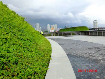 View of footpath against cloudy sky