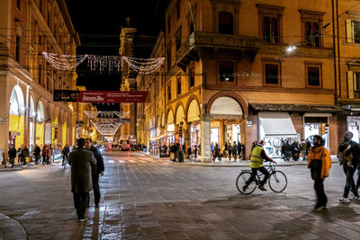 People on street against illuminated buildings in city at night