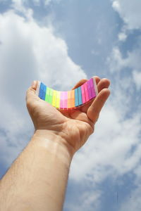 Midsection of man holding multi colored paper against sky