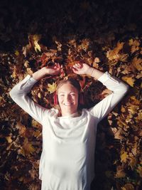 Portrait of smiling young woman standing by tree during autumn