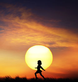 Silhouette man standing against orange sky