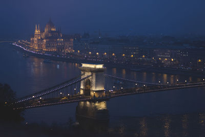 Illuminated chain bridge over river at night