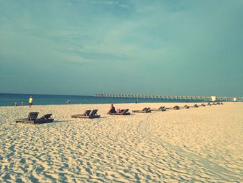 Lounge chairs on sandy beach against sky