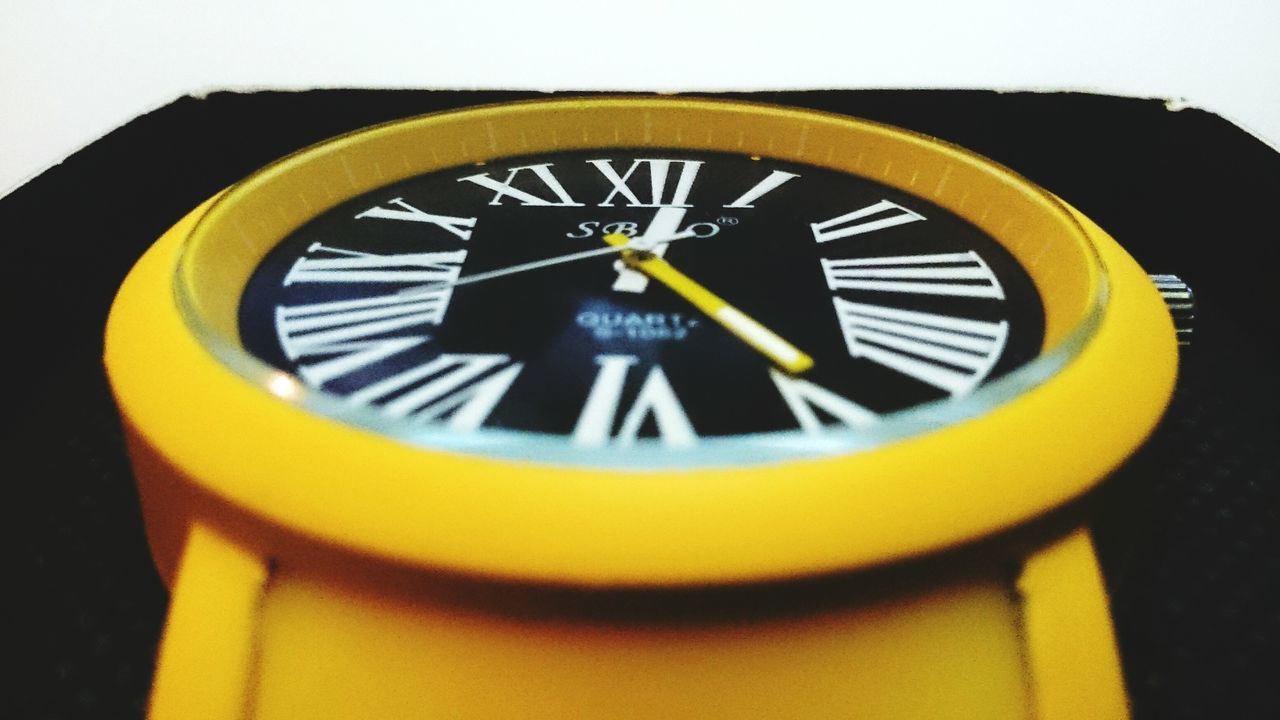 yellow, circle, close-up, geometric shape, time, clock, text, communication, number, single object, round, no people, clock face, day, western script, minute hand, metal, blue, outdoors