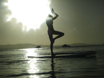 Silhouette of woman jumping on beach