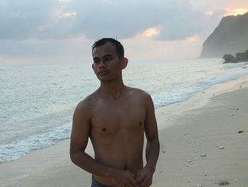 Young man standing on beach against sky