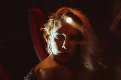 Close-up portrait of young woman against black background