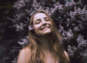 Portrait of smiling teenage girl against flowering plants at park