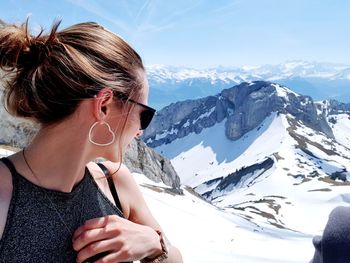 Woman wearing sunglasses against snowcapped mountains