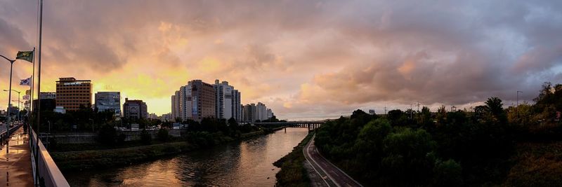 Panoramic view of river amidst buildings against sky during sunset