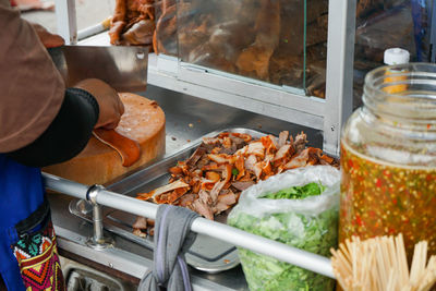 Delicious stewed ear pork at the street food. motion blurred hand of seller chops the pork on board.