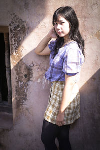 Beautiful young woman standing against wall