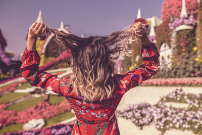 Midsection of woman with arms raised against sky