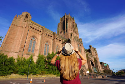 Girl looking the cathedral church of christ against blue sky in liverpool on sunset, united kingdom