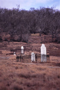 Low angle view of tombstones amidst fence on mountain