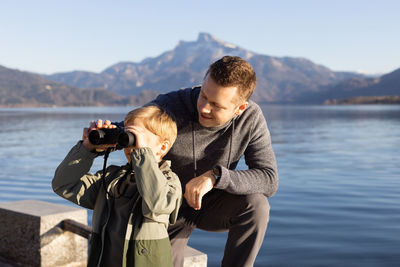 Father looking at son looking through binocular