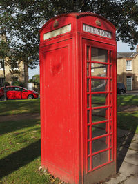 Red telephone booth by trees