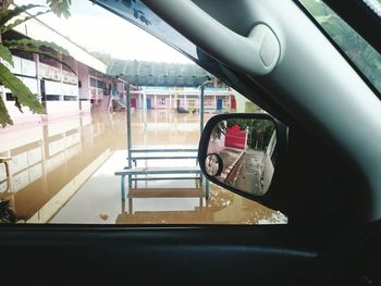 Reflection of man on side-view mirror of car