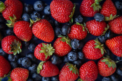 Background of assorted fresh berries of red juicy strawberries and blue blueberries close-up.