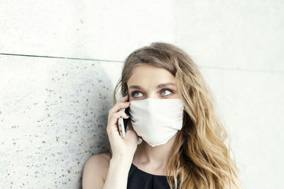 Portrait of young woman against wall