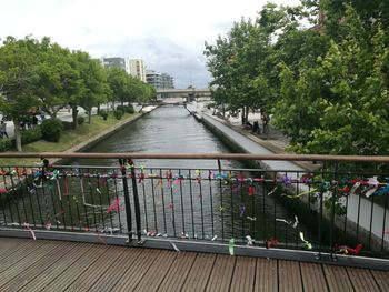 Footbridge over river in city against sky