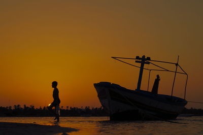 Men in sea against sky during sunset
