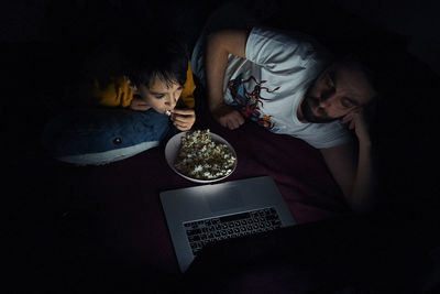 High angle view of father and sun watching movie on laptop