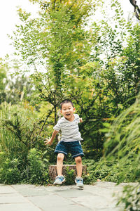 Full length portrait of cute boy against trees