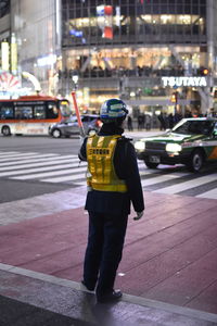 Rear view of man standing on street at night