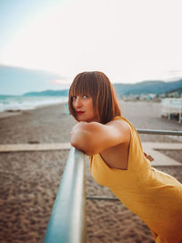 Portrait of woman at beach against sky