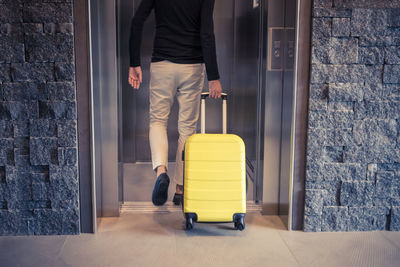 Low section of man with luggage entering elevator in hotel