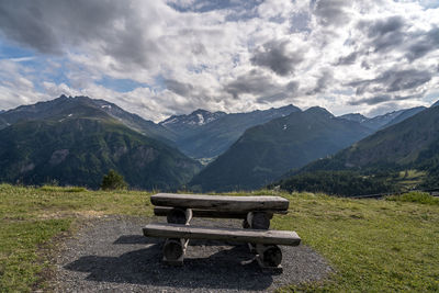 Empty bench on mountain range against sky