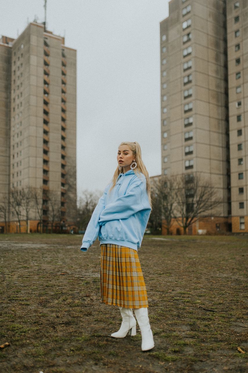 FULL LENGTH PORTRAIT OF WOMAN STANDING ON BUILDING IN CITY