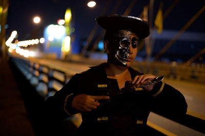 Young man wearing pirate costume standing on bridge at night