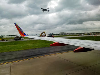 Airplane flying over airport runway against sky