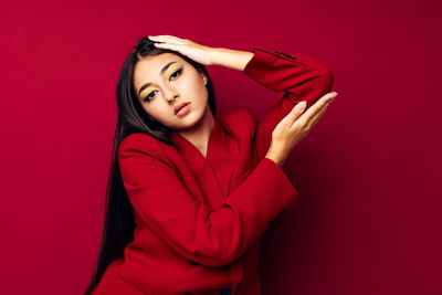 Portrait of young woman standing against yellow background