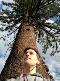 Low angle view of young man against tree