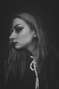 Close-up portrait of young woman against black background