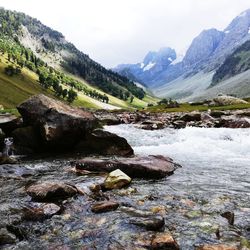 Scenic view of river by mountains against sky