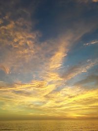 Scenic view of sea against dramatic sky during sunset