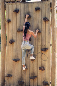 Full length rear view of woman climbing on artificial wall