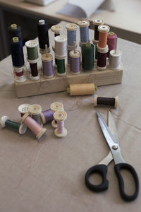 High angle view of various thread spools and scissors on table