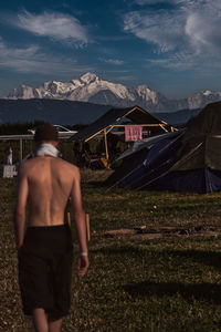 Rear view of shirtless man standing on field against sky and facing the mont-blanc