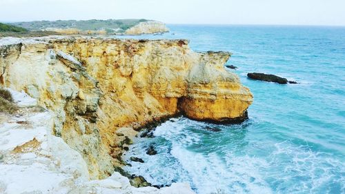 Rock formation in sea against sky