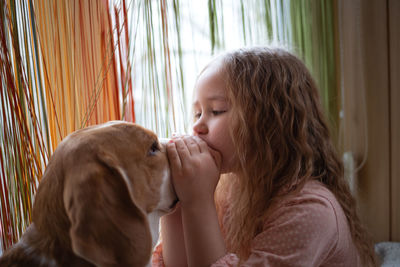Side view of girl playing with dog at home