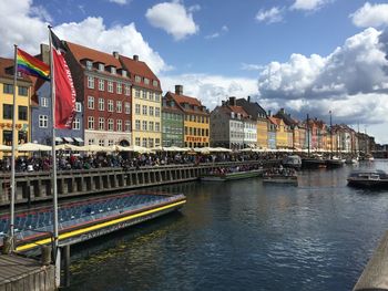 Buildings by river against sky in city