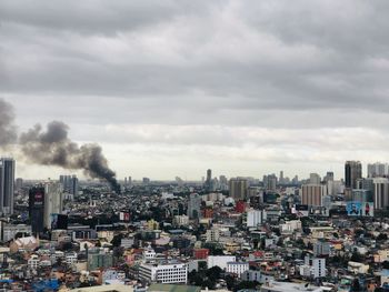 Buildings in city against sky with building on fire