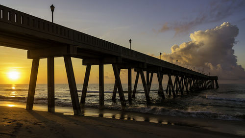 Pier over sea against sky during sunset