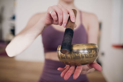 Close-up of woman holding singing bowl at home